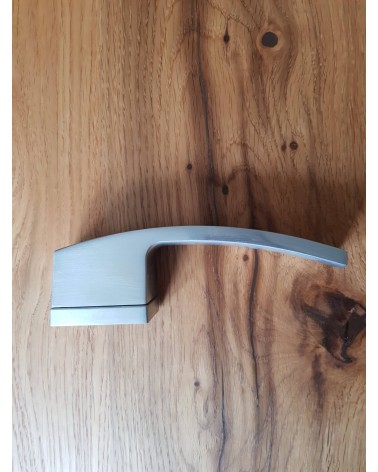 Puxador de porta cromado acetinado Arc design vista de lado pousado numa placa
