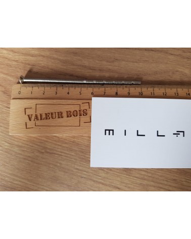 Varão roscado passante M4 de 10cm de comprimento sobre uma mesa, com uma régua de madeira e cartão de visita branco millapoignee