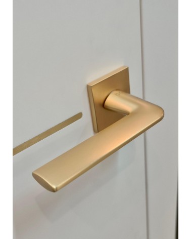 Puxador de porta dourado mate STINGER puxador design visto de cima inclinado montado numa porta