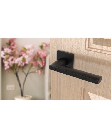 Puxador de porta preto PYROLA ferragens design vista inclinada montado numa porta