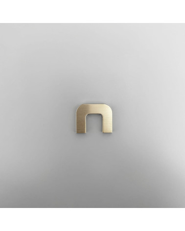 Puxador de móvel em latão dourado polido ISA XS design vista frontal sobre superfície cinzenta