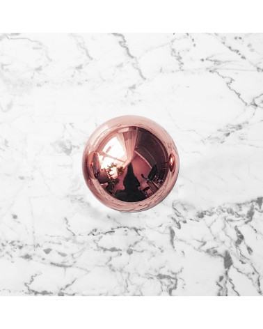 Botão de móvel cobre ODETE M puxador design visto de cima sobre uma superfície marmorada