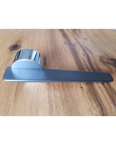 Puxador de porta bicolor JUMELLE puxador design visto de lado colocado sobre uma placa