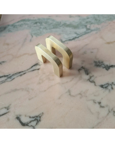 Puxador de móvel em dourado polido ISA XS design em perspetiva diagonal colocado plano sobre uma superfície em mármore