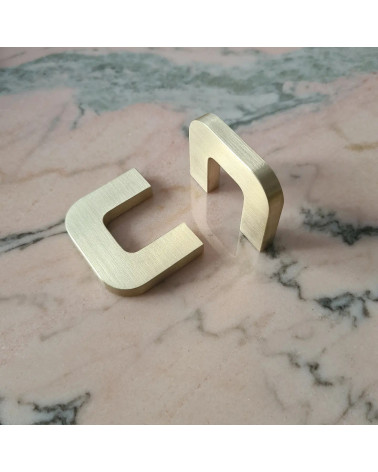 Puxador de móvel em latão dourado polido ISA XS design colocados perpendicularmente sobre uma superfície marmorizada