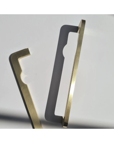 Puxador de móvel em latão ISA DOT design pousado verticalmente sobre uma superfície cinzenta