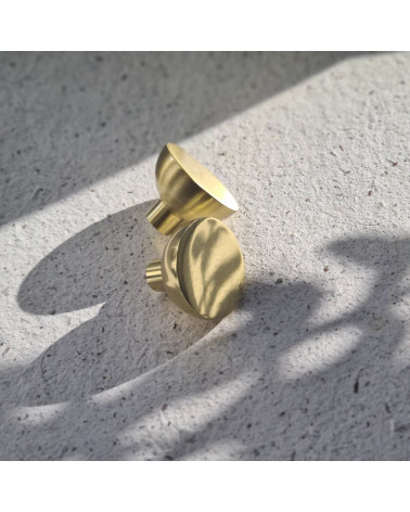 Puxador de móvel dourado polido LUNA M design pousado sobre cimento