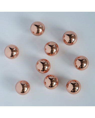 Puxador de móvel em cobre ODETE M design dispostos de forma aleatória sobre uma superfície branca com reflexos brilhantes