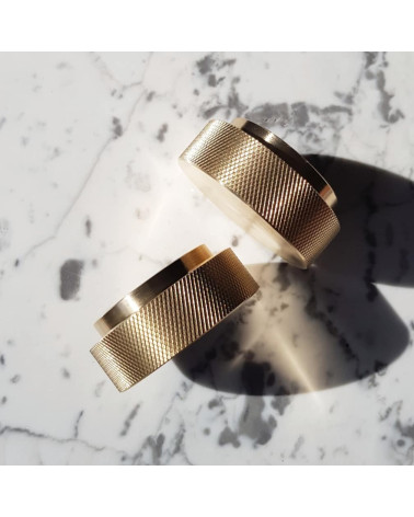 Botão de móvel dourado mate TOVE puxador design inclinado vista de cima sobre uma superfície marmorizada branca com sombras