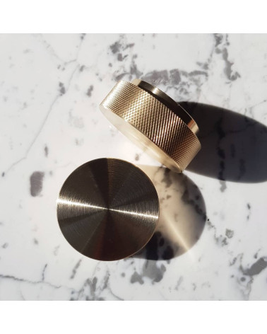 Botão de móvel dourado mate TOVE puxador design vista de cima ligeiramente inclinados pousados sobre uma superfície marmorizada 