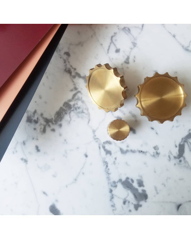 Botão de móvel dourado polido LEXI puxador design colocado sobre uma placa marmorizada