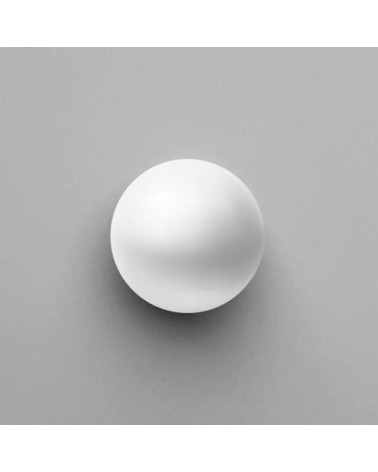 Botão de móvel branco ODETE puxador design visto de cima pousado sobre uma superfície cinzenta
