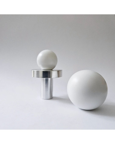Botão de móvel branco ODETE puxador design vista de frente pousado sobre uma superfície cinzenta