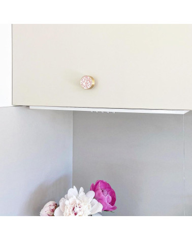 Puxador de móvel em latão e Pink Terrazzo design instalado num móvel com flores rosas em baixo