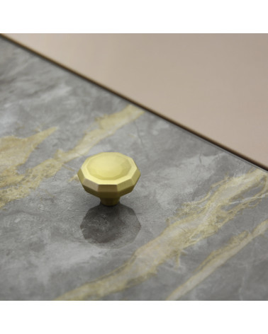Puxador de móvel dourado mate CAMPANA design pousado sobre uma superfície plana com fundo texturado
