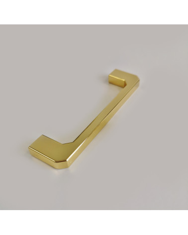 Puxador de móvel dourado polido CAMPANA design pousado sobre uma superfície cinzenta